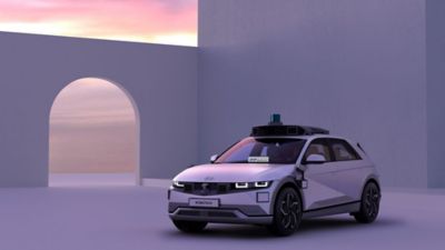 The IONIQ 5 robotaxi shown from the front in the purple light of a sunset.