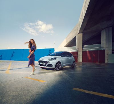 Femme debout devant une Hyundai i10 N Line.