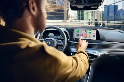 Muž na sedadle vodiča ovláda dotykovú obrazovku nového modelu Hyundai i20
