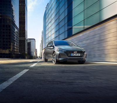 La Hyundai i20 garée à côté de grands immeubles dans une rue autrement vide.