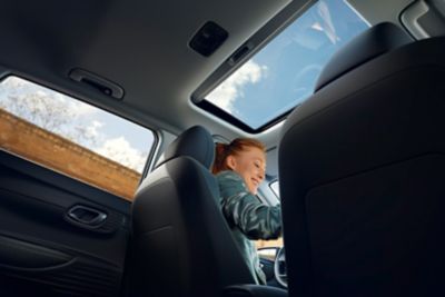 Pohľad zo zadného sedadla nového modelu Hyundai i20 cez nové otvorené panoramatické okno