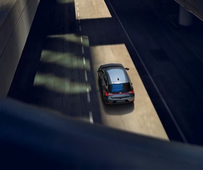 A grey Hyundai i20 on the road, drone view from the rear top