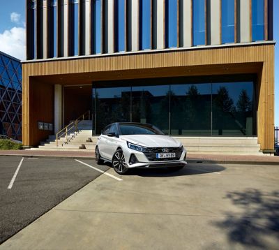 Une Hyundai i20 N Line blanche garée devant un bâtiment.