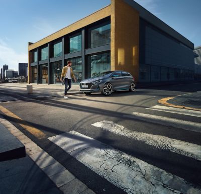 Muž stojaci pri novom modeli Hyundai i20 pred budovou s veľkými oknami
