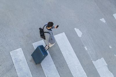 Hombre con smartphone cruzando la carretera mientras mira la guía de navegación hasta el último metro.