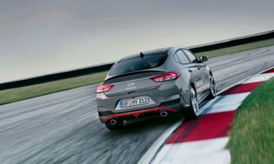 Vista trasera del Hyundai i30 Fastback N tomando una curva en circuito.