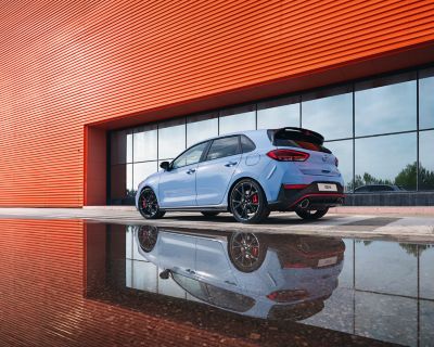 the i30 N performance hatchback from an angle, parked next to a reflective surface.