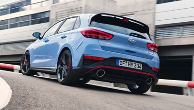 A Hyundai i30N in Performance Blue driving around a corner dynamically.