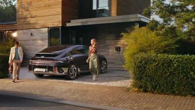 La berline 100 % électrique quatre portes Hyundai IONIQ 6 branchée au boîtier mural d’une maison.