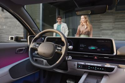 The inside of the Hyundai IONIQ 6 and two persons coming in front of it.