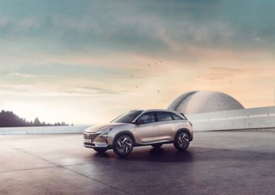 Vue latérale de Hyundai NEXO au crépuscule, devant un bâtiment futuriste.