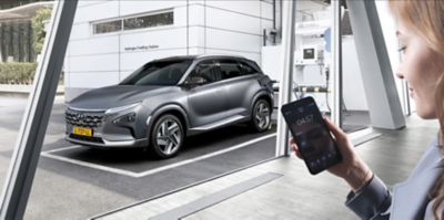 A woman standing before the all-new Hyundai Nexo before a city panorama.