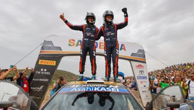 Hyundai Motorsport driver Ott Tänak and Martin Järveoja standing on their rally car, celebrating.