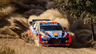 The Hyundai i20 N WRC Rally1 for the 2022 WRC driving through sandy terrain.