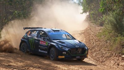 Hyundai i20 N Rally2 throwing up dust in a curve during a rally.