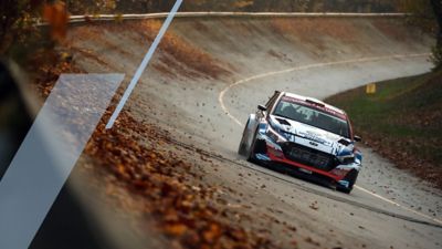 Hyundai i20 N Rally2 on a race track covered in fallen leaves