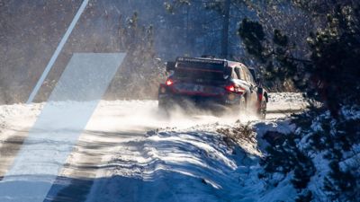 The Hyundai i20 N WRC rally race car taking a sharp turn during a winter race.