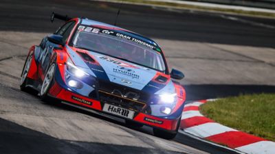  The Hyundai Motorsport’s i30 N TCR in action on a racetrack pictured from the front.