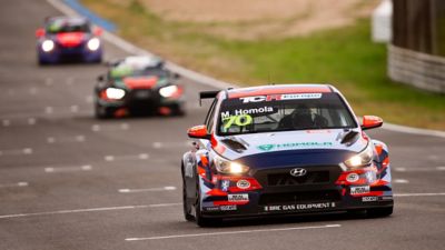  The Hyundai Motorsport’s i30 N TCR in action on a racetrack in a corner.