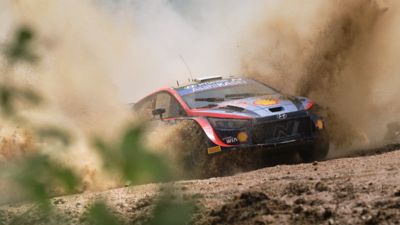 The Hyundai i20 N WRC rally race car churning through gravel during a race.