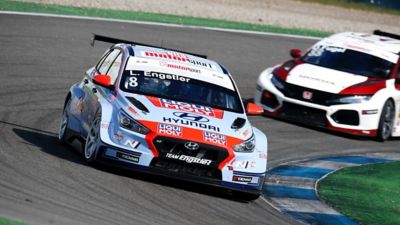 The Hyundai Motorsport’s i30 VELOSTER N TCR in action on a racetrack shown from the side.