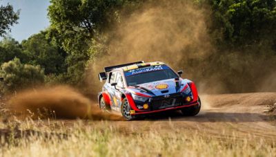 Thierry Neuville's Hyundai i20 WRC drifting around a corner on a sandy road.