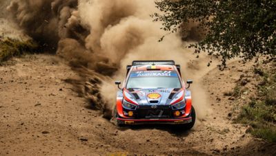 Motor sport driver Thierry Neuville's Hyundai i20 WRC speeding through sandy terrain.