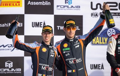 Hyundai WRC driver Thierry Neuville & Martijn Wydaeghe on the podium with champagne.