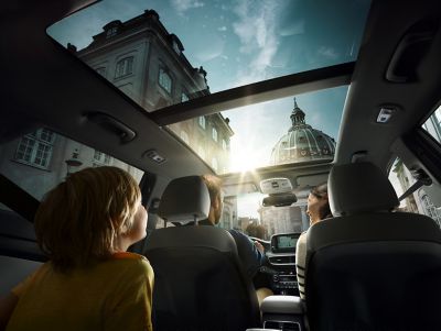 Looking inside a Hyundai through the windshield, a family in the car is looking happy.