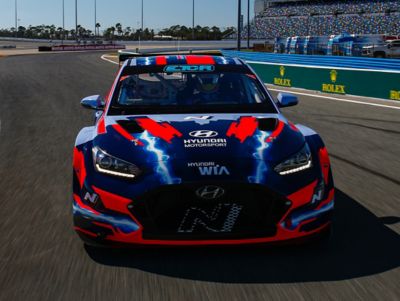 The Hyundai VELOSTER N ETCR from the front on a racetrack.