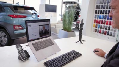 A Hyundai dealer during a live video chat with a customer via laptop.