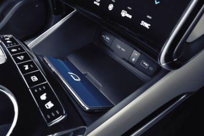 Odkládací prostor pro vysokorychlostní bezdrátové nabíjení uvnitř zcela nového kompaktního SUV Hyundai Tucson.