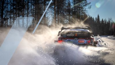 Vůz Hyundai i20 Coupe WRC vytváří na sněhu vodní tříšť. 