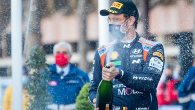 Hyundai Motorsport-piloot Nicolas Gilsoul met spuitende champagnefles om een overwinning te vieren