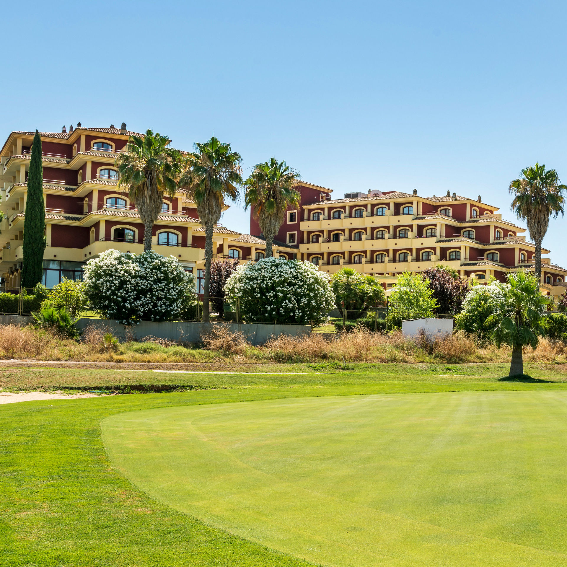 pista de golf con el hotel ILUNION Golf Badajoz en el fondo 