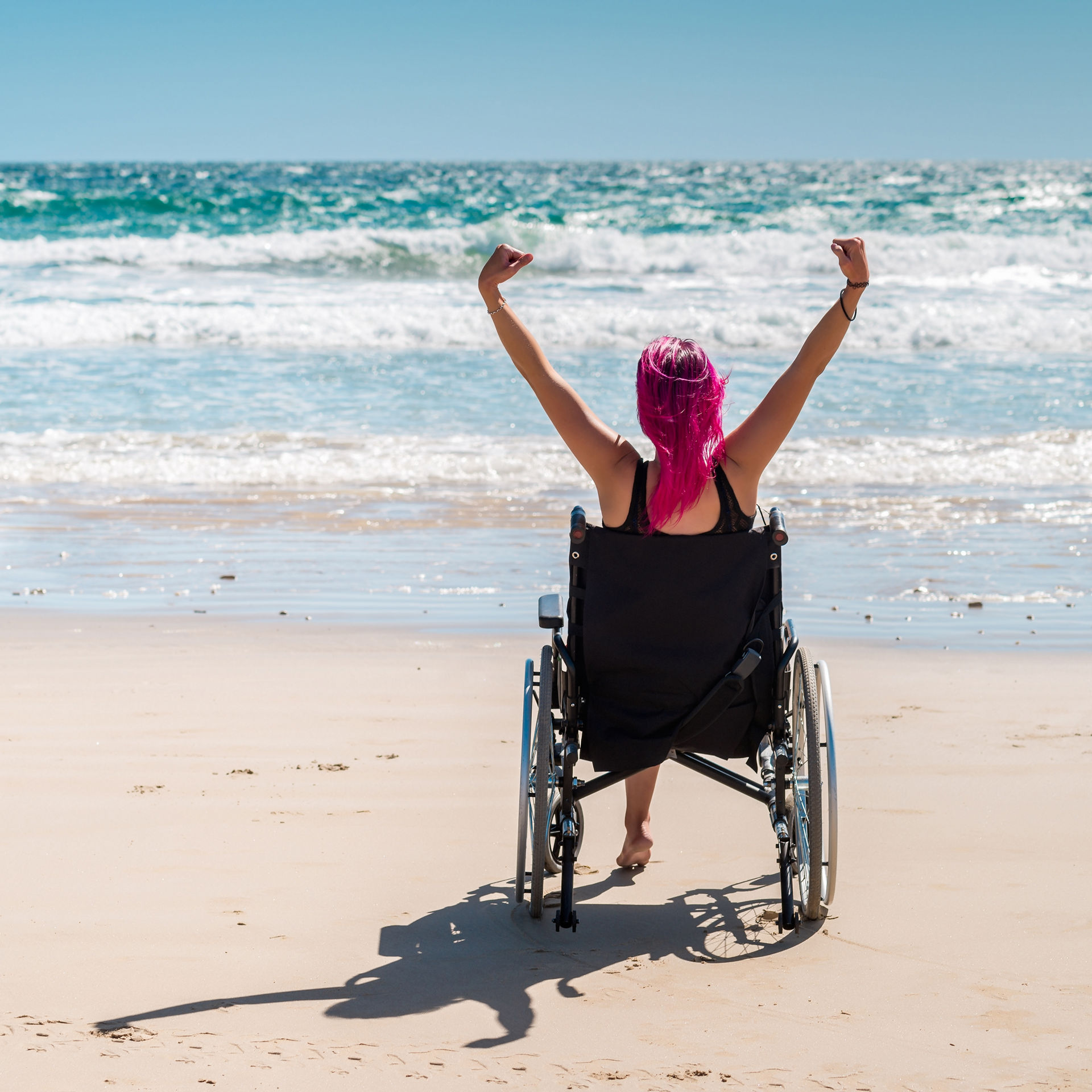 una chica llega rápidamente al mar en su silla de ruedas