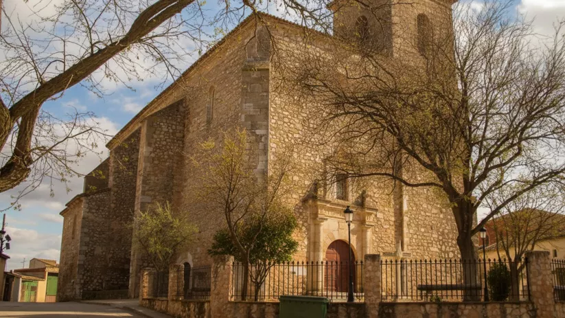 Iglesia de piedra junto a árboles y verja