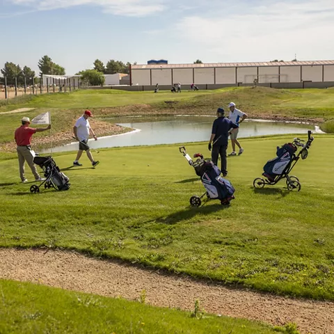 Grupo de jugadores en el green junto a un estanque