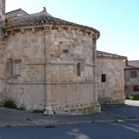 Ábside románico de piedra con muros curvos y tejado de teja.