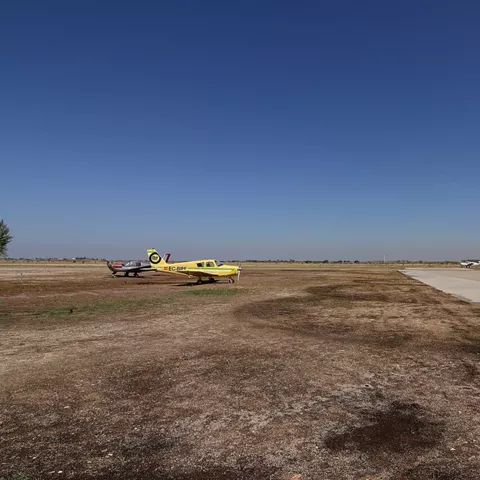 Pequeñas aeronaves estacionadas junto a una pista en entorno rural.