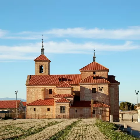 Vista posterior de iglesia de ladrillo junto a campos de cultivo