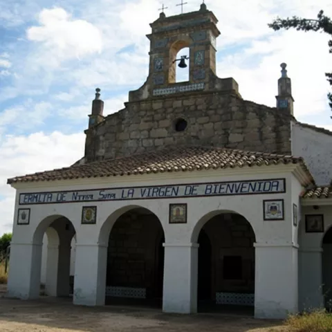 Fachada de ermita de piedra con espadaña y arcos