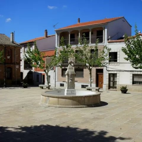 Plaza urbana con fuente central y viviendas tradicionales