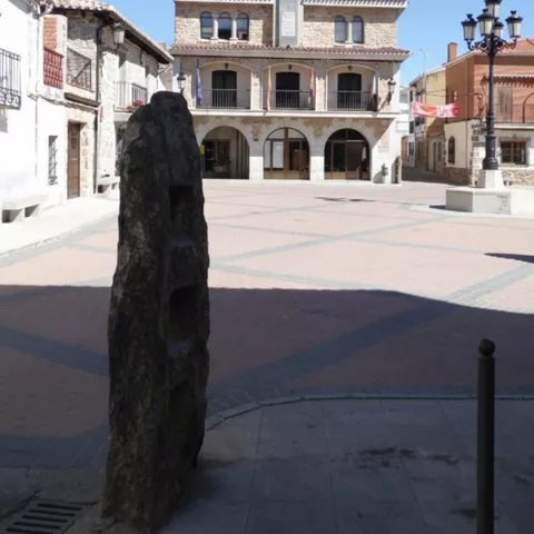 Plaza empedrada con edificio porticado y torre con reloj
