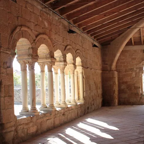 Pasillo porticado con columnas y techo de madera.