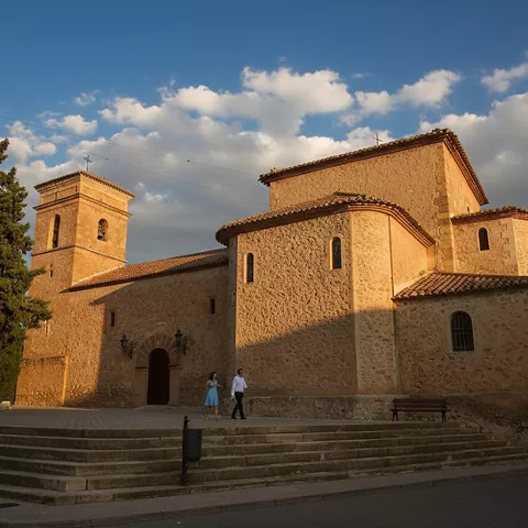 Iglesia de piedra iluminada por la luz del atardecer con personas paseando.