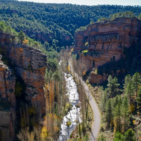 Carretera junto a río entre altos acantilados.