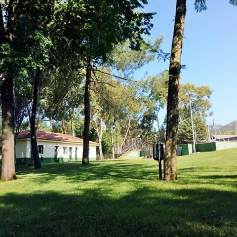 Jardín arbolado junto a edificio blanco de una planta