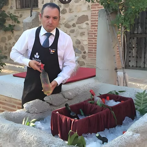 Camarero junto a botellas frías en un patio de piedra