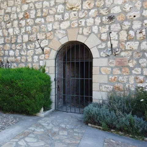 Entrada de piedra con arco y reja metálica.